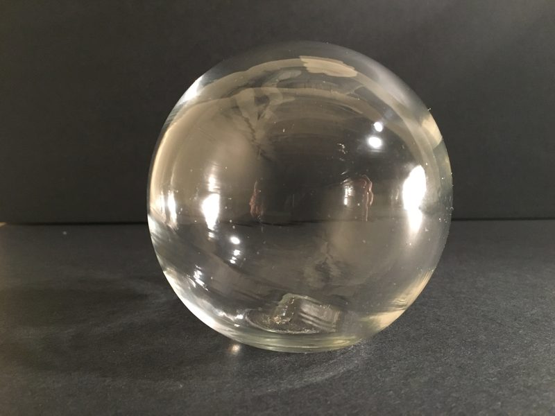 Clear solid glass sphere on a grey surface