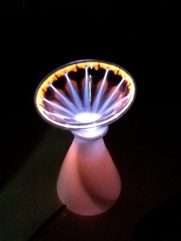 Plasma discharge fanning out inside a glass bowl on a frosted pink stem