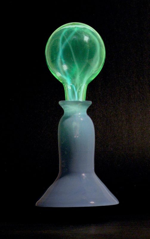 Green plasma filaments glowing in a clear globe atop a pale blue glass base